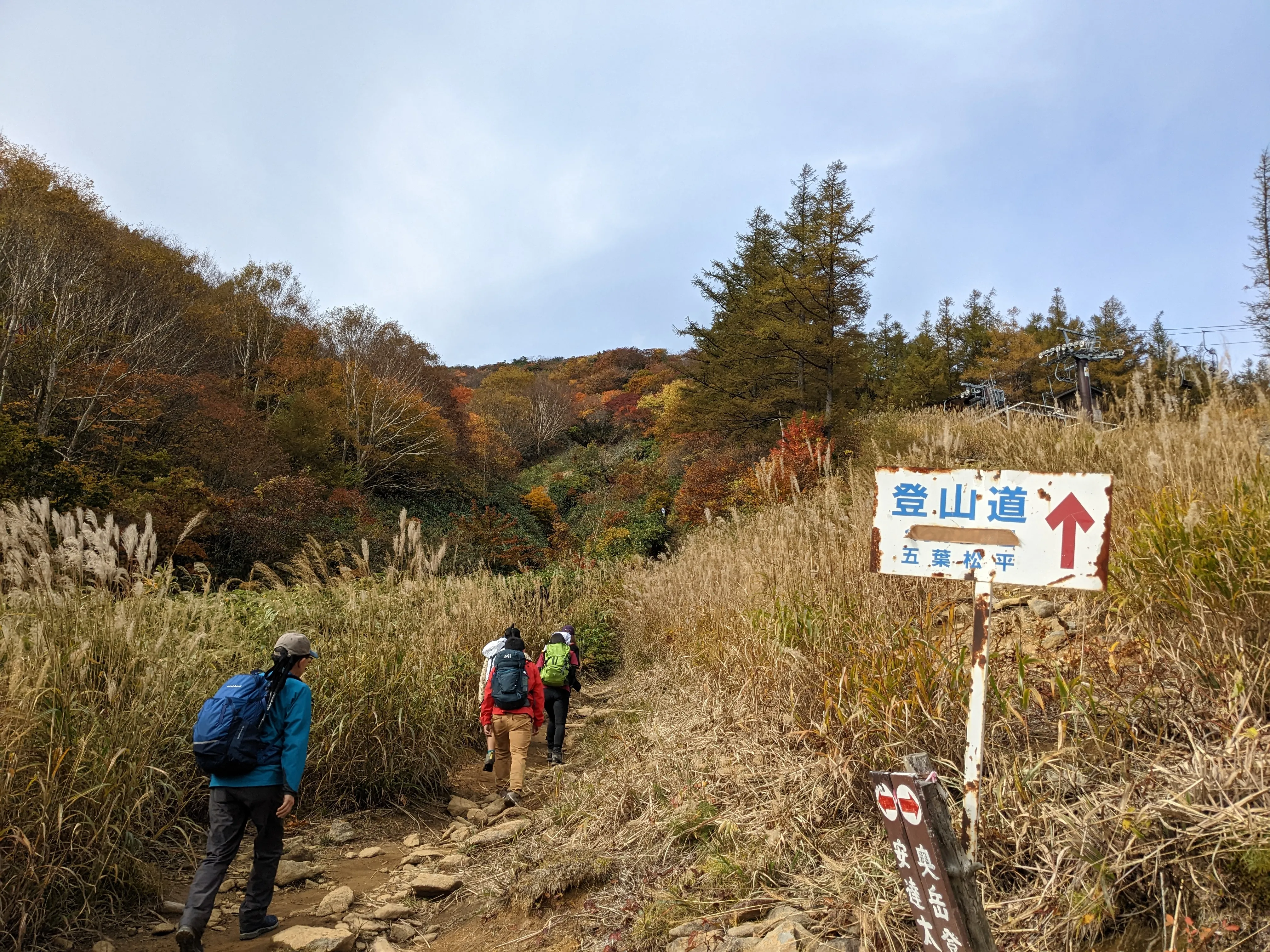 People hiking up a trail, with a sign marking that it's the hiking path.