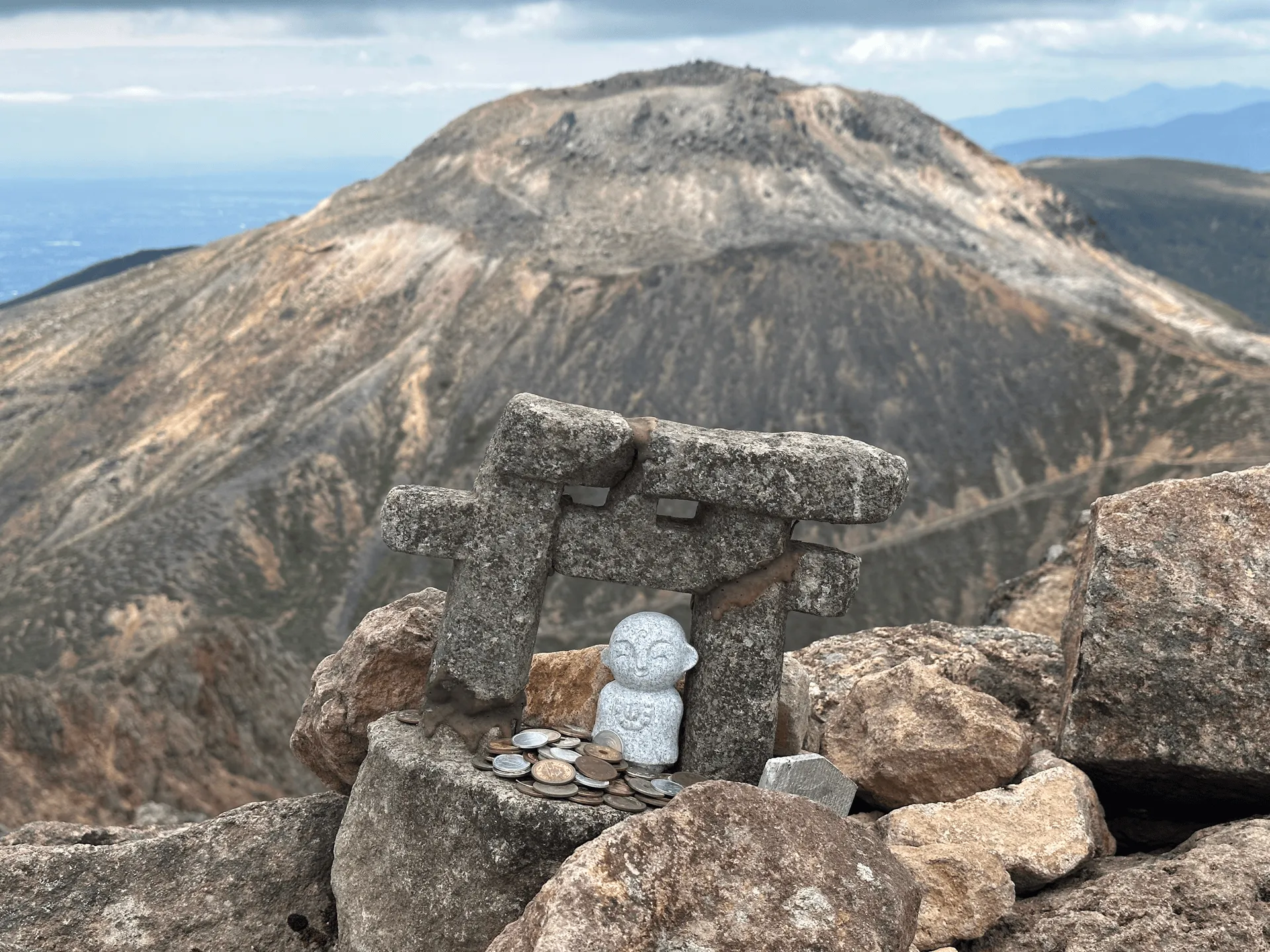 A closeup of a shrine, with Mt Chausu's peak visible in the distance behind it
